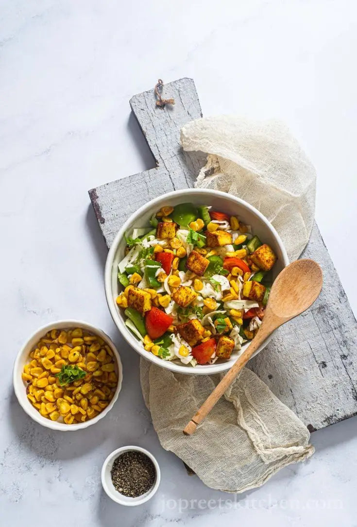 Colorful salad with vegetables and tofu in a bowl on a light surface